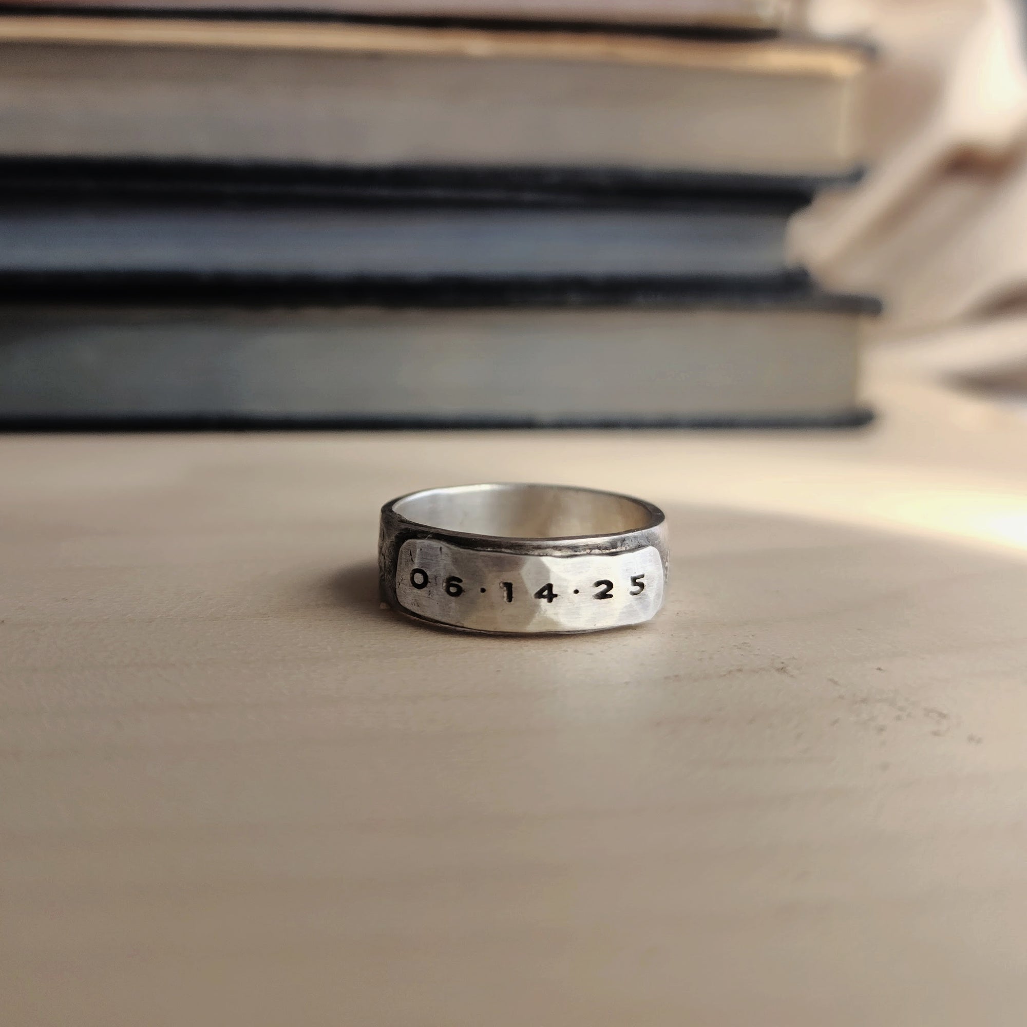 Silver ring with engraved numbers on a stone surface