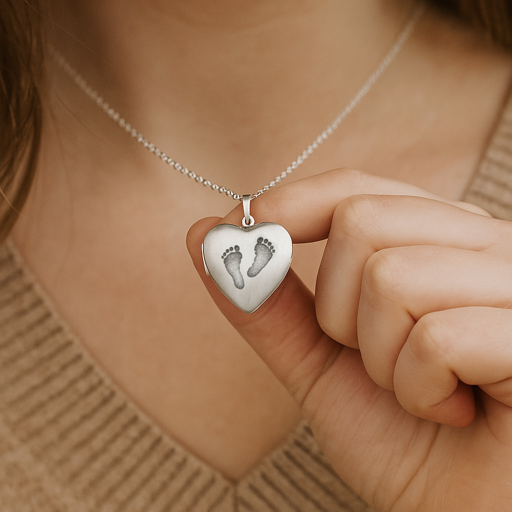 Heart-shaped pendant with footprints held by a hand