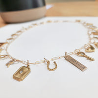 Gold charm bracelet with various charms on a white surface