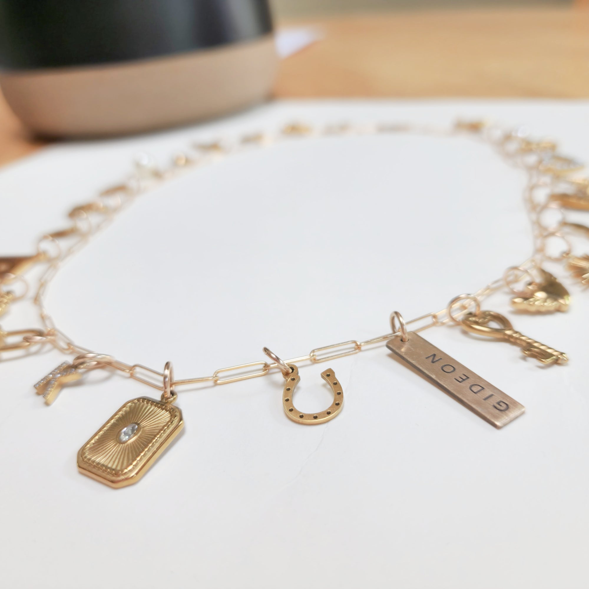 Gold charm bracelet with various charms on a white surface