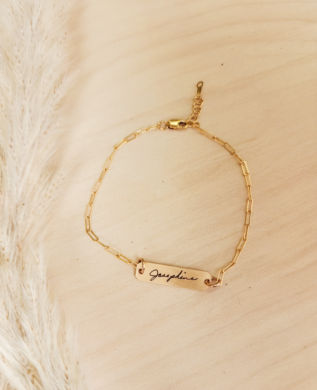 A gold-filled bracelet with a personalized signature tag on a person's wrist, showing the name 'Josephine'.