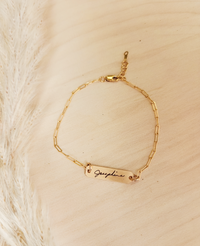 A gold-filled bracelet with a personalized signature tag on a person's wrist, showing the name 'Josephine'.