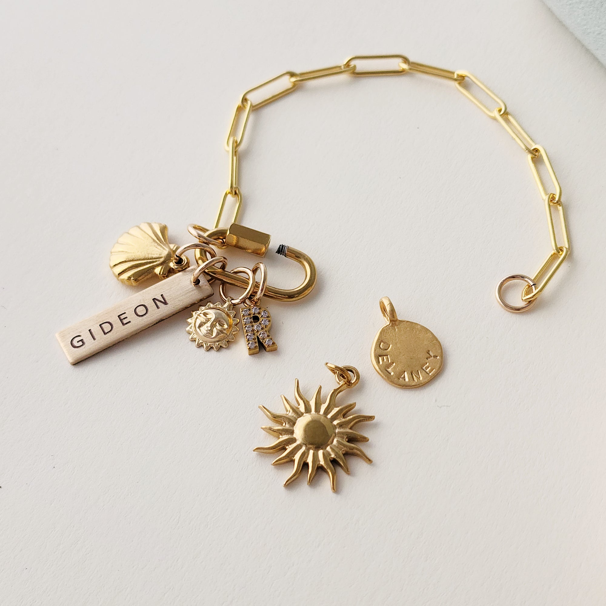 Gold bracelet with various charms on a light gray background