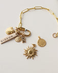 Gold bracelet with various charms on a light gray background