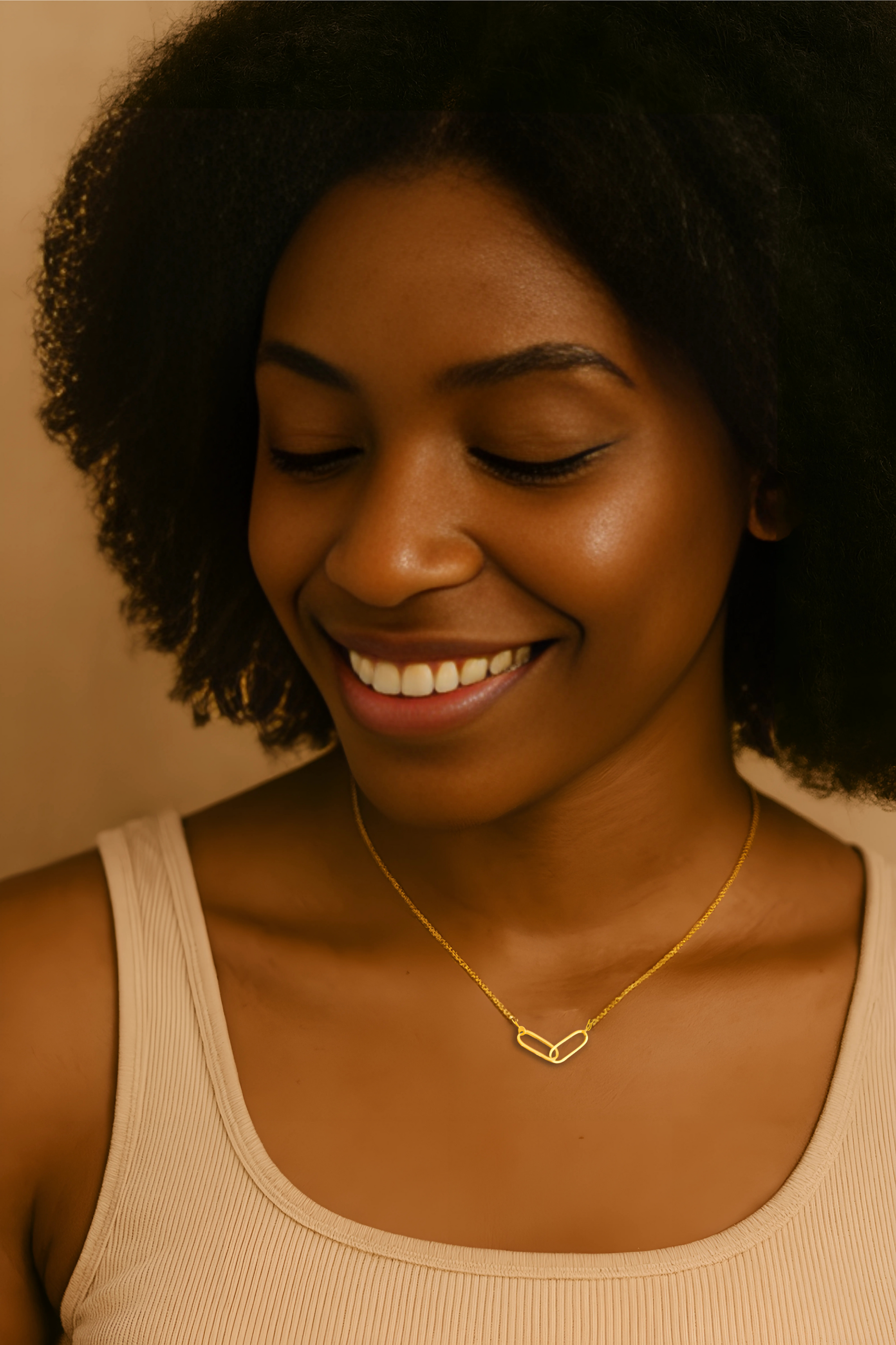 Woman wearing a gold necklace with a heart-shaped pendant against a neutral background