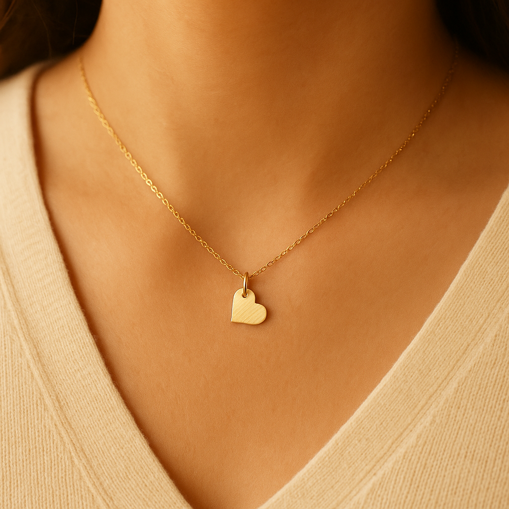 Gold heart necklace on a person wearing a beige top