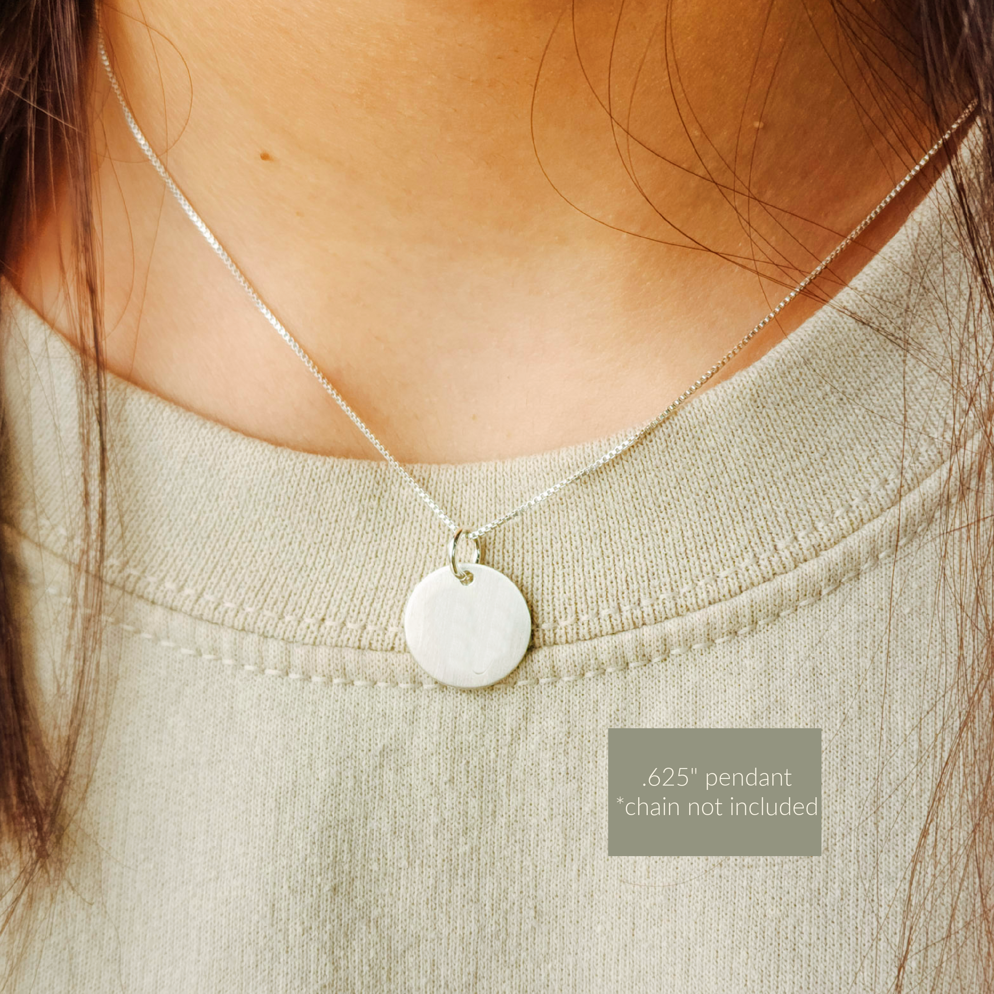 Close-up of a silver pendant necklace on a person wearing a light green top.