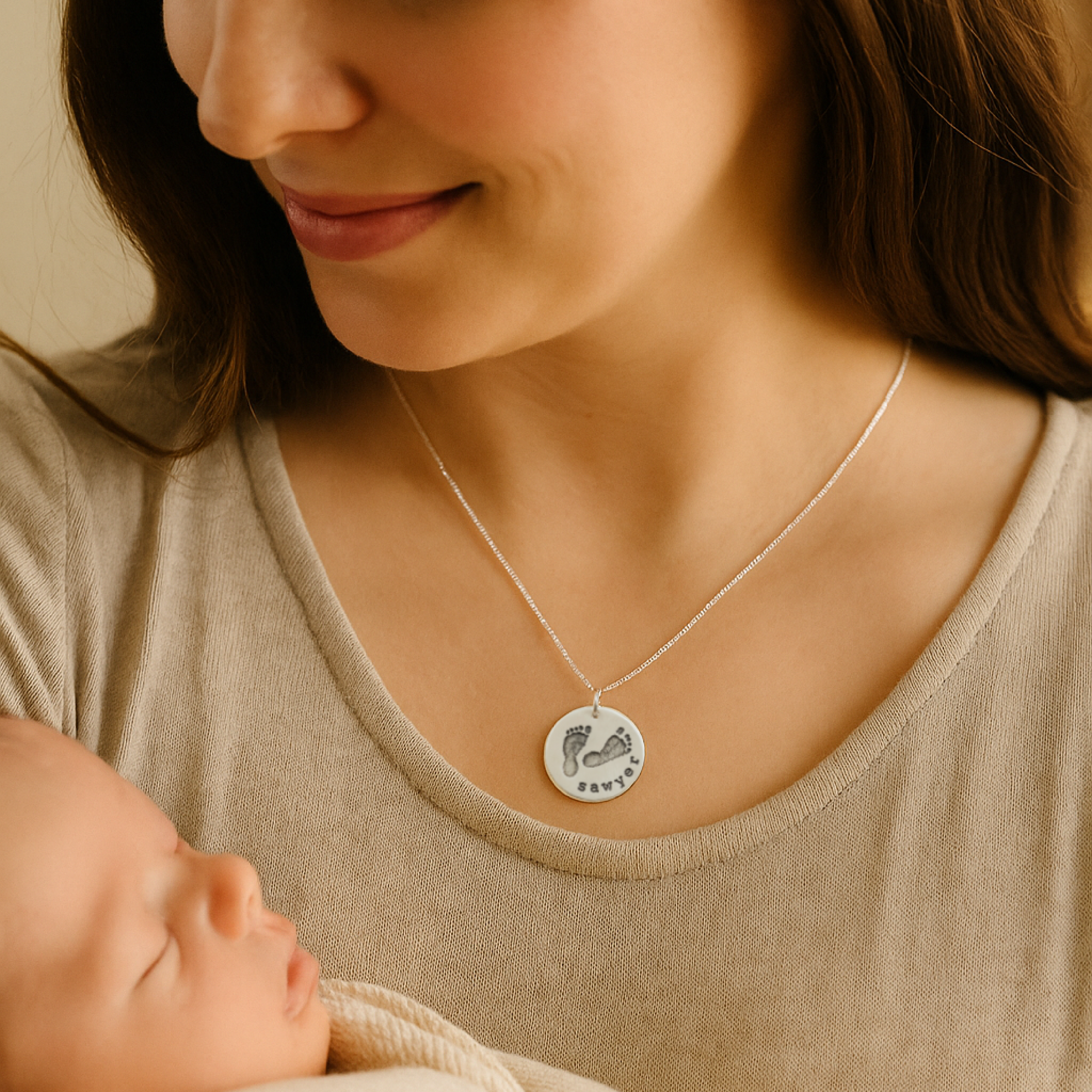 Woman wearing a necklace with a pendant, holding a baby