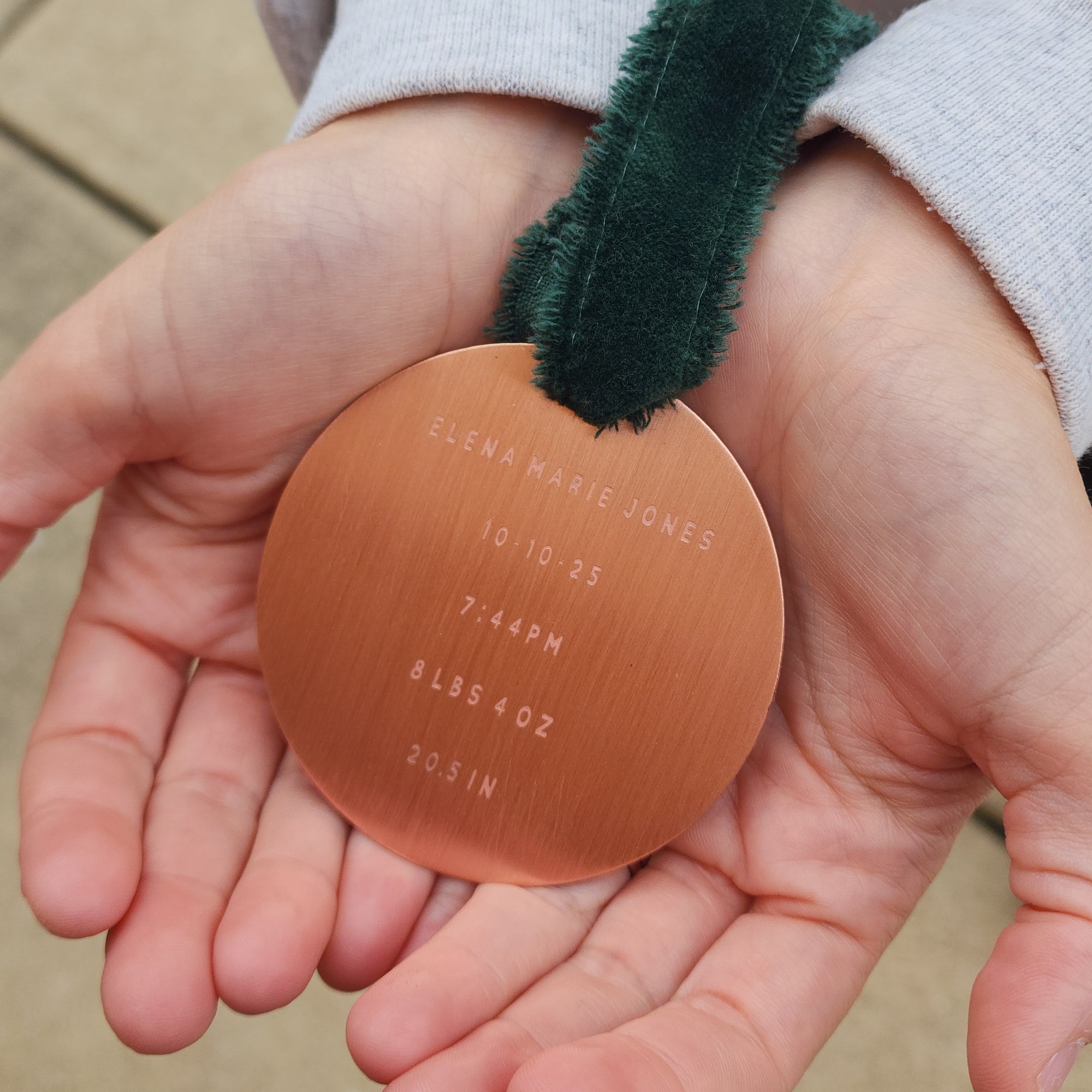 Copper baby ornament held in hands with engraved details