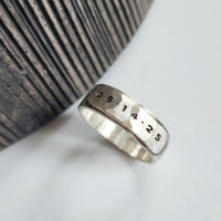 Silver ring with engraved numbers on a textured surface