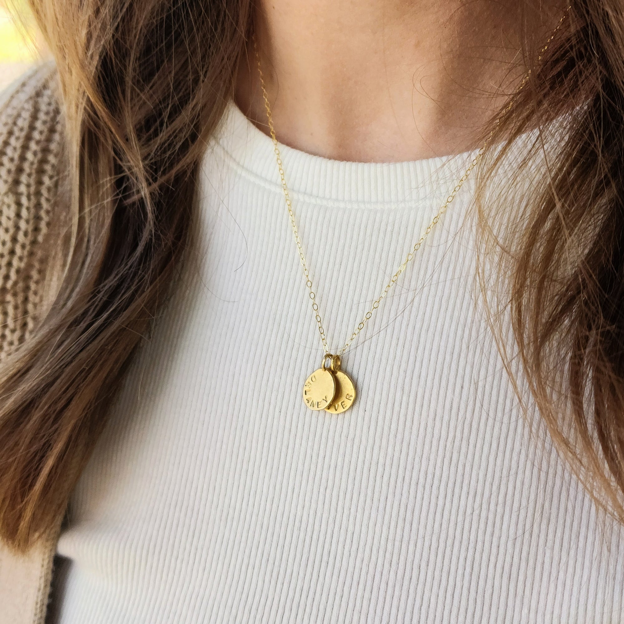 Gold necklace with two round pendants on a white shirt