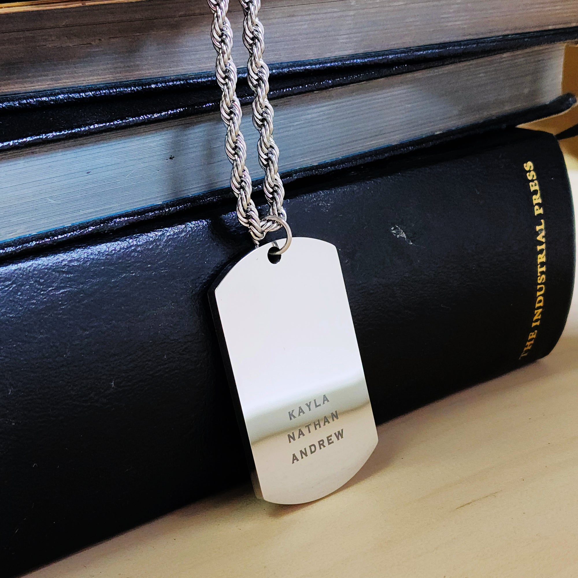 Dog tag necklace with engraved names on a black surface
