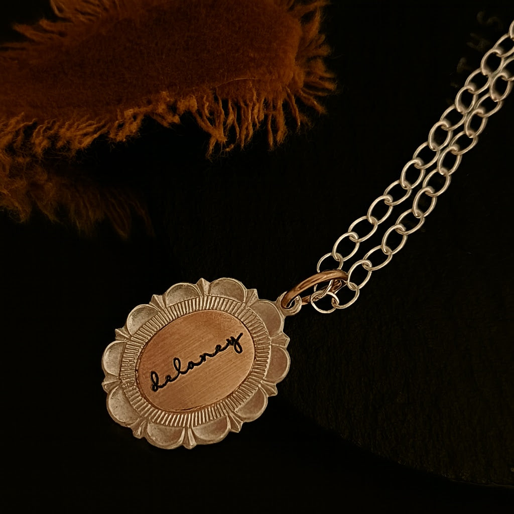 Gold necklace with a round pendant engraved with 'balance' on a dark background.