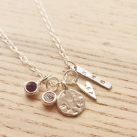 Silver necklace with various charms on a wooden surface