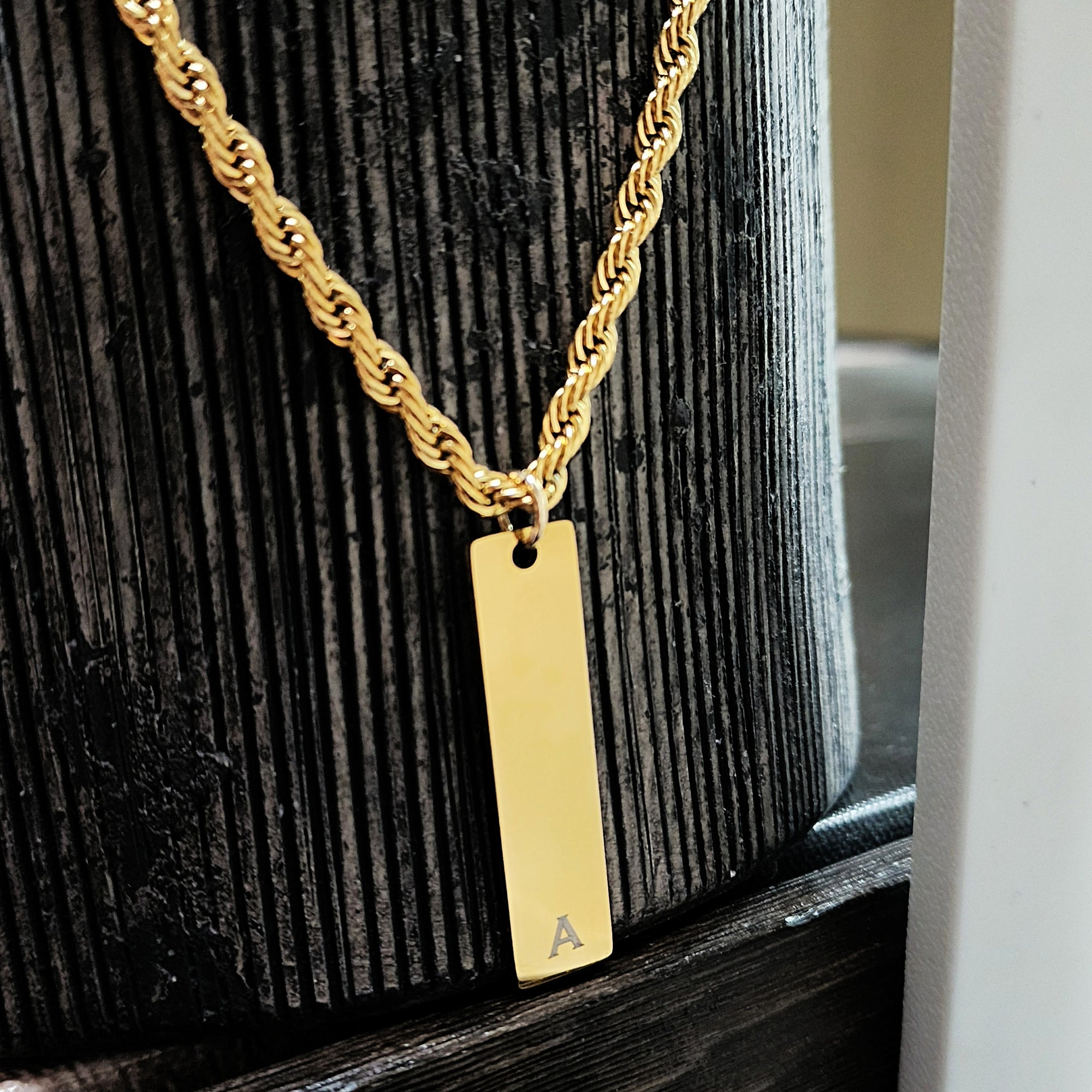 Gold necklace with a rectangular pendant on a wooden surface
