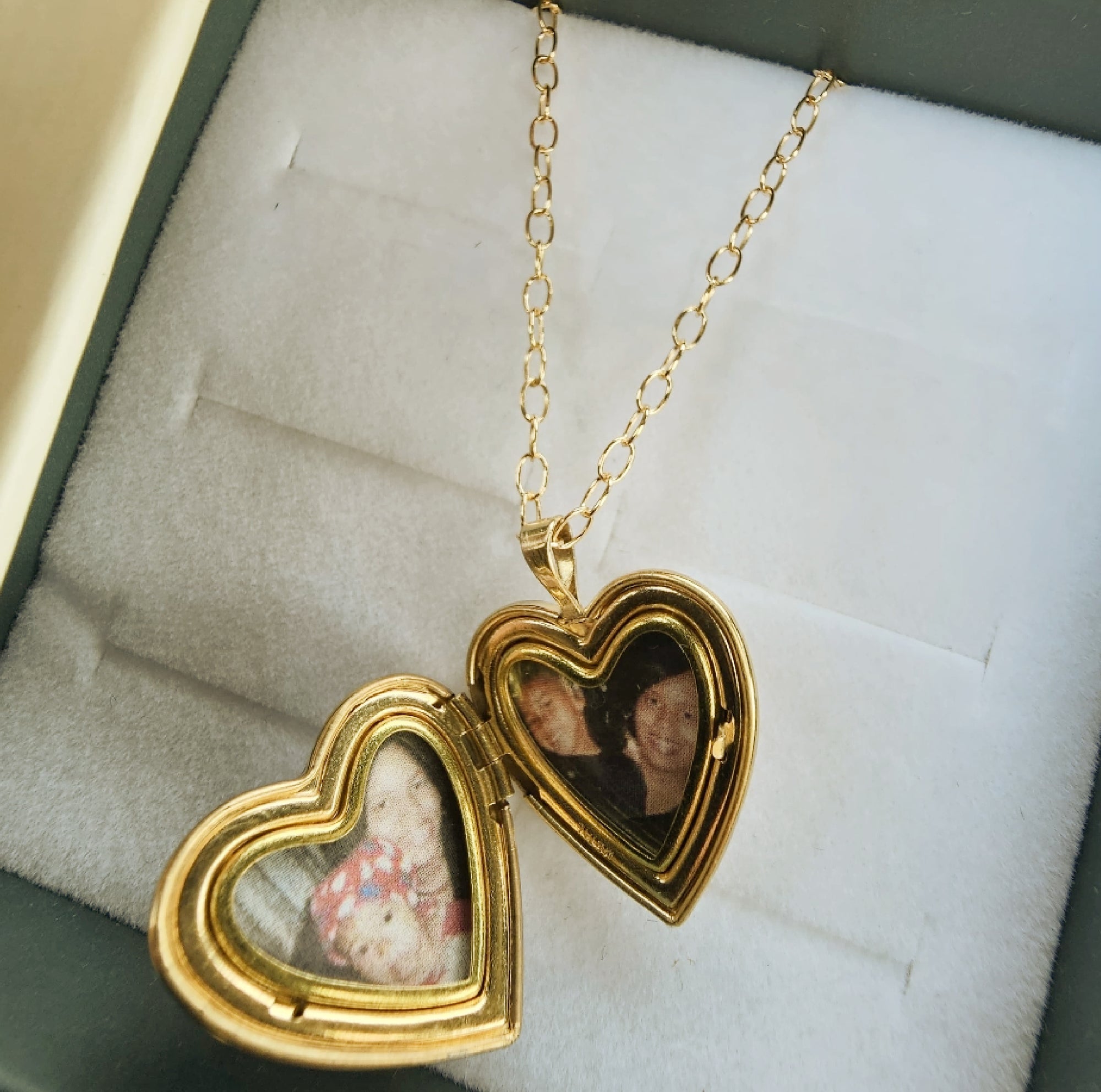 Gold heart-shaped locket with embedded photos on a soft surface