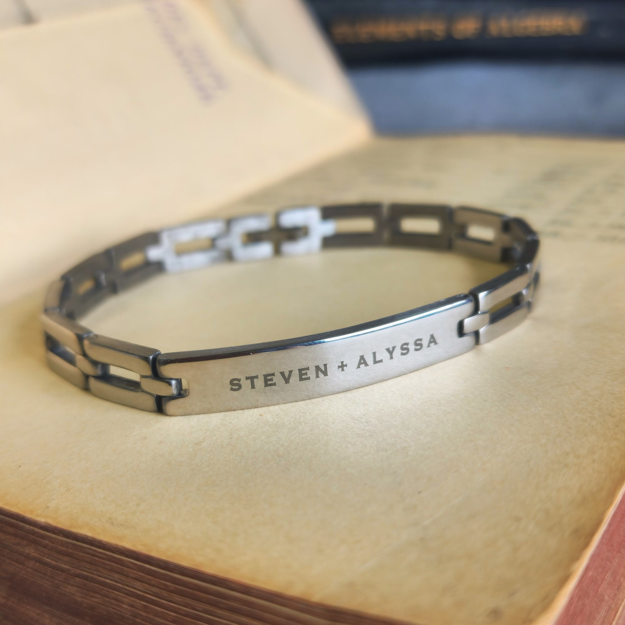 Silver bracelet with engraved names on an old book