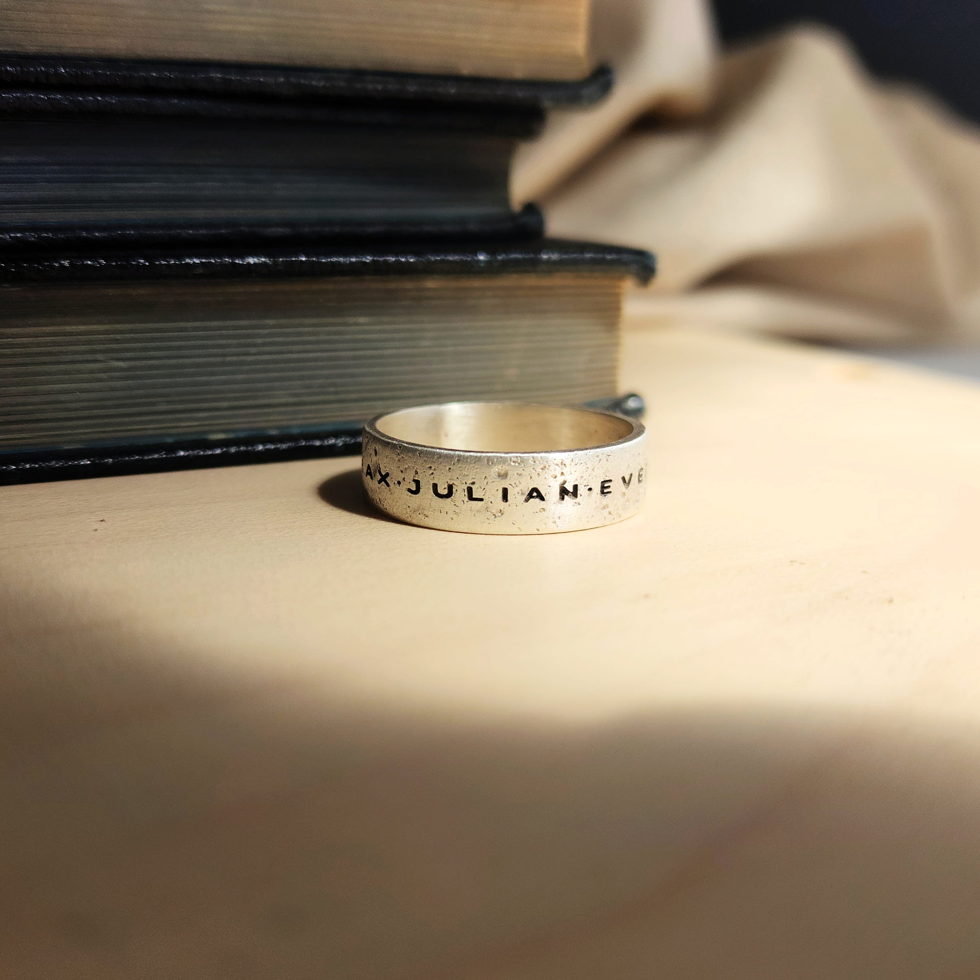 Silver ring with engraved text on a stack of books