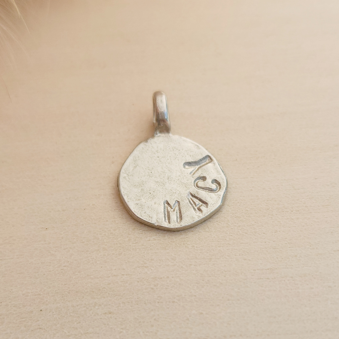 Silver pendant with 'Macy' engraved on a beige background