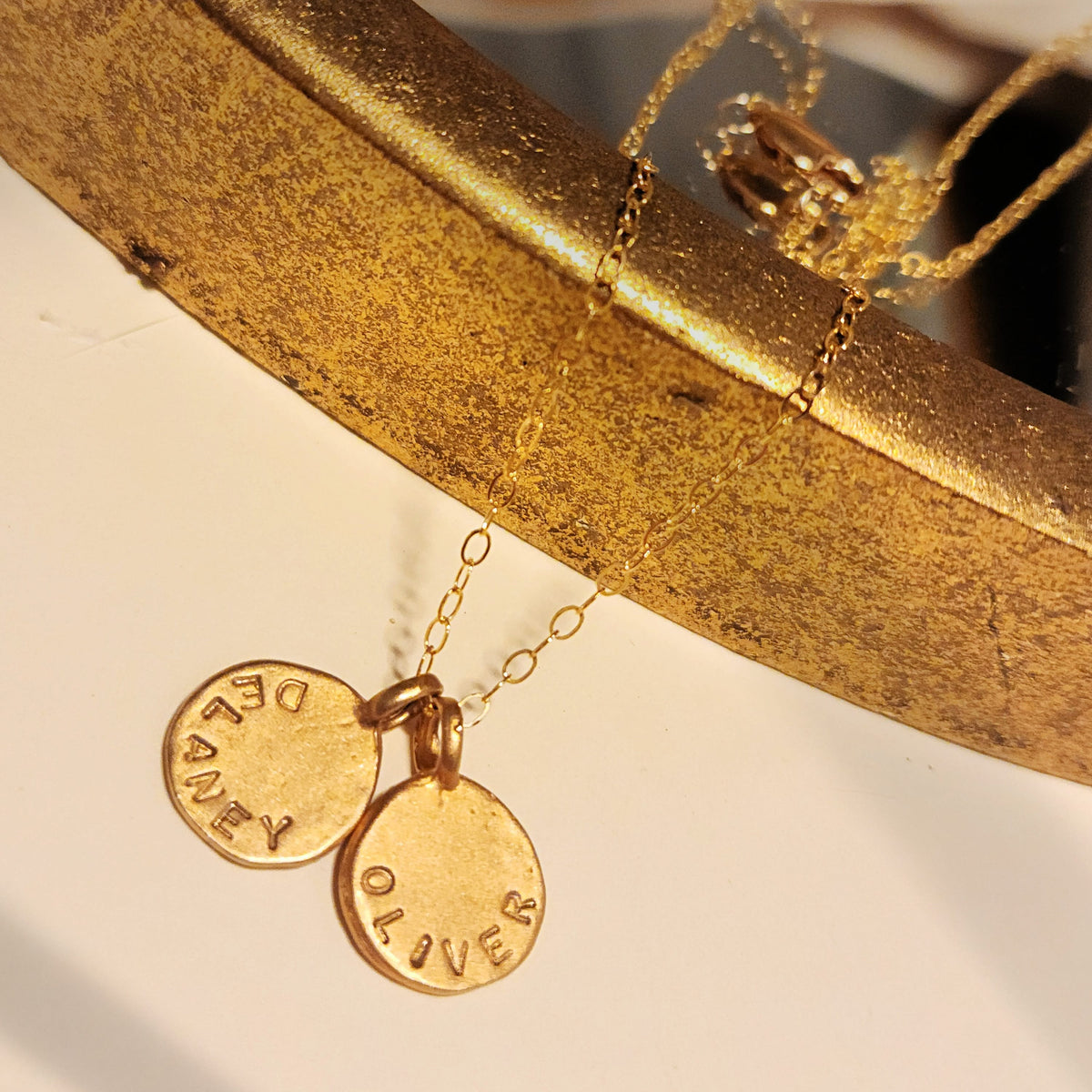 Gold necklace with engraved pendants on a gold stand