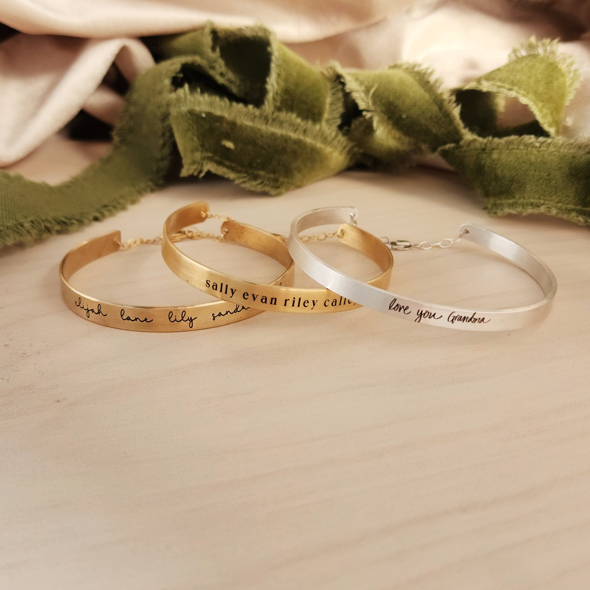 gold and silver handwriting cuff bracelet on wood table