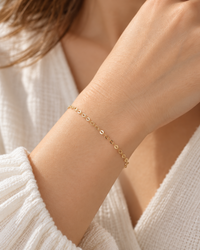 Delicate gold cable bracelet on woman's wrist in soft light
