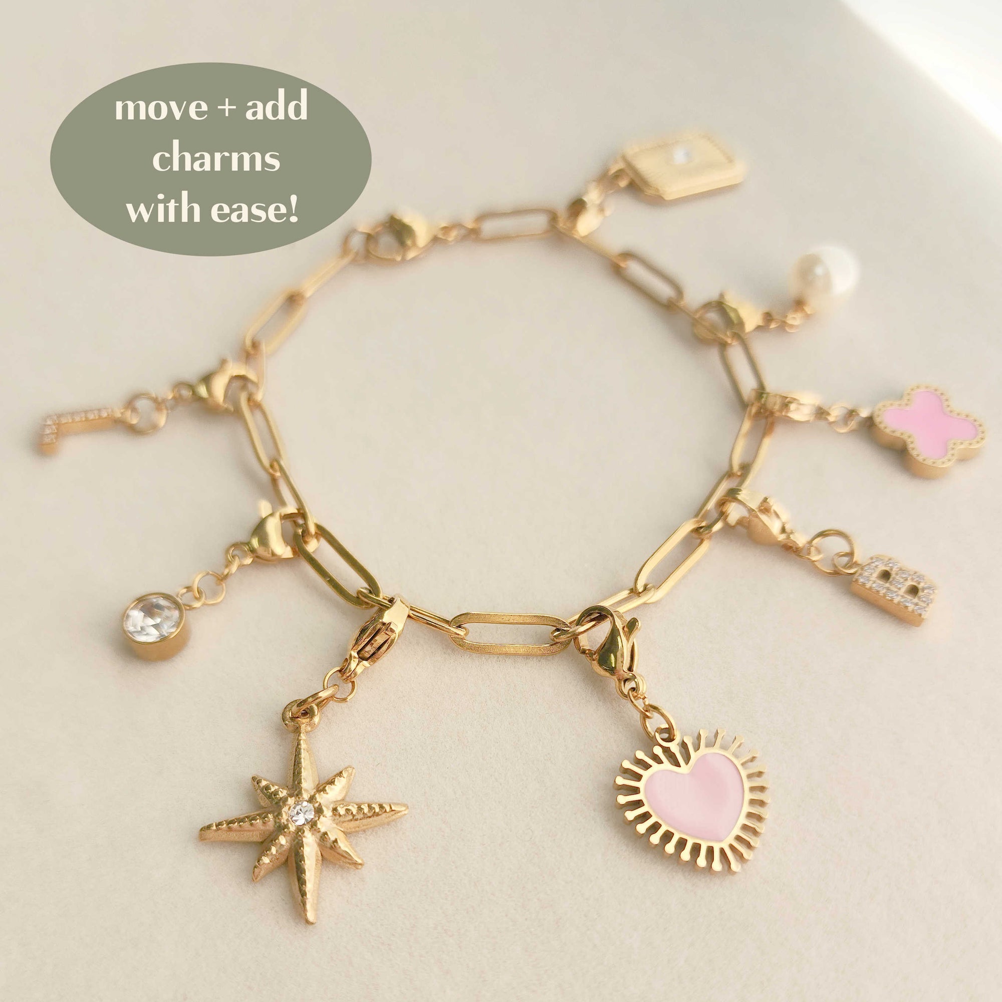 A gold charm bracelet with interchangeable charms including a star and a heart, displayed on a neutral background.
