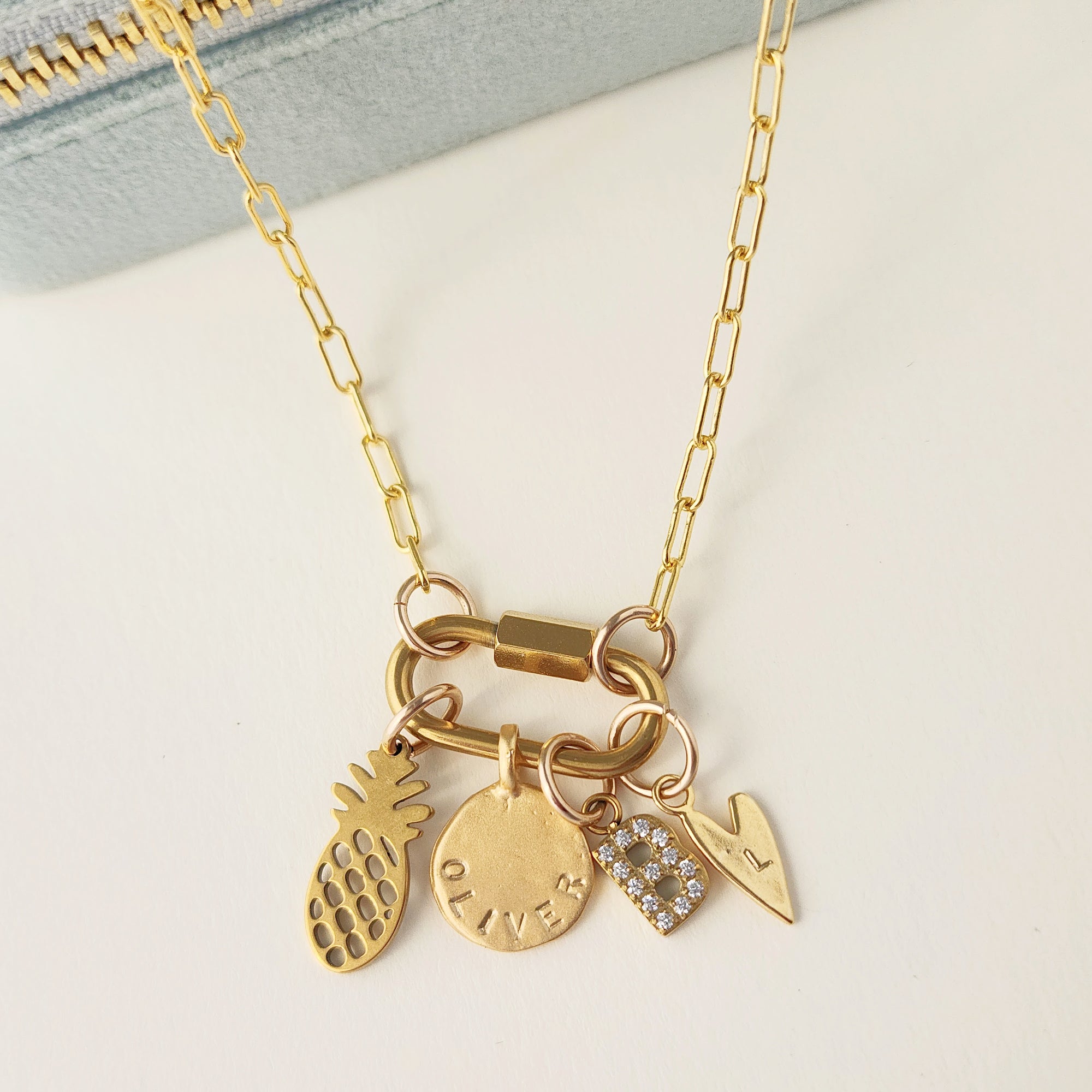 Gold necklace with various charms on a light background