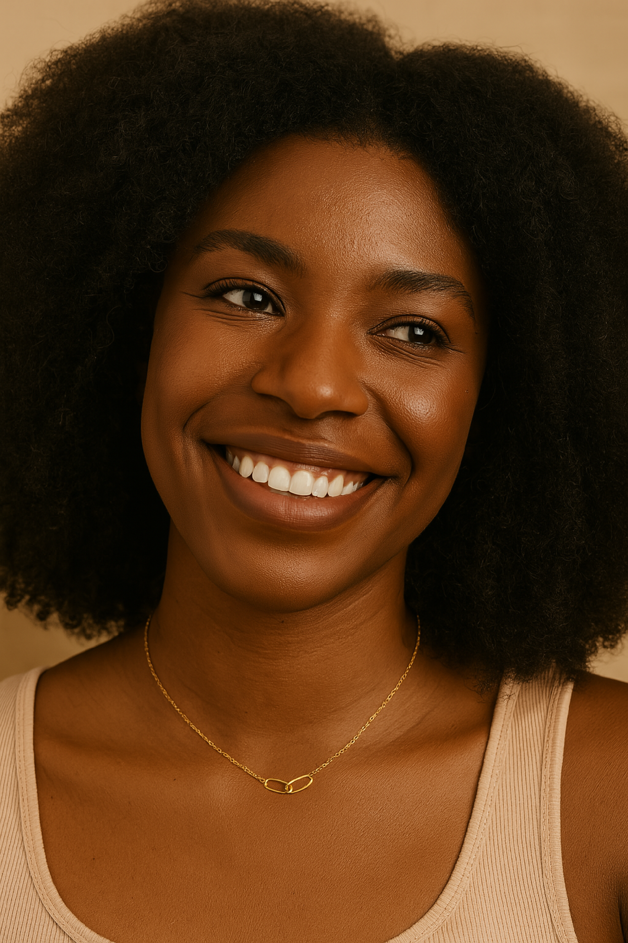 Woman with a warm smile wearing a beige tank top and gold necklace against a neutral background