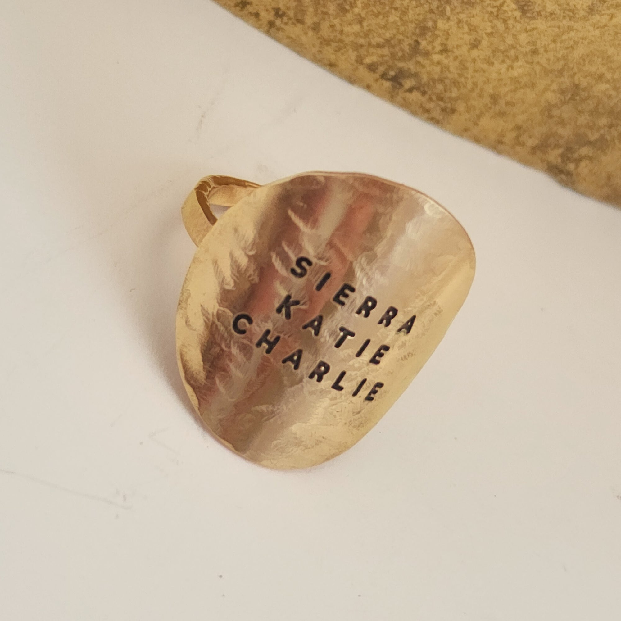 Gold pendant with engraved names on a beige background