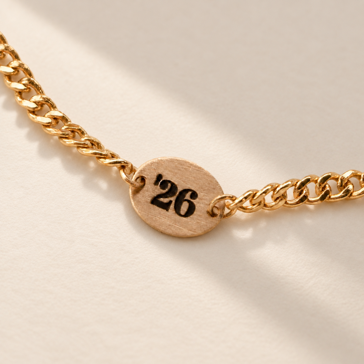 Brushed gold chain tag with '26 engraved