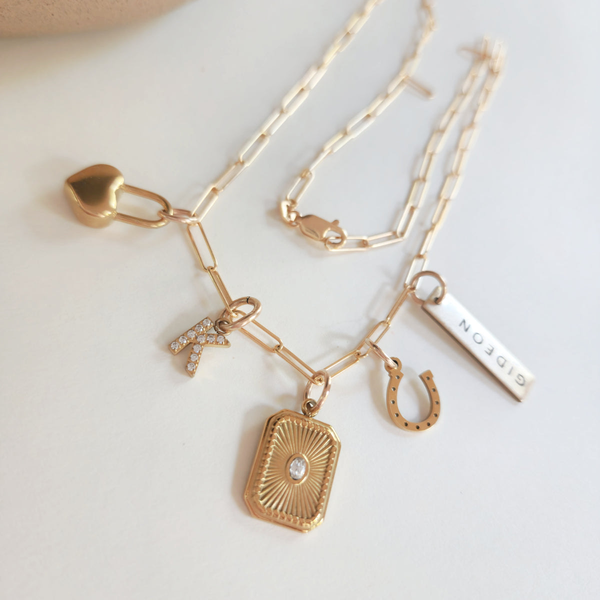 Gold necklace with various charms on a light background