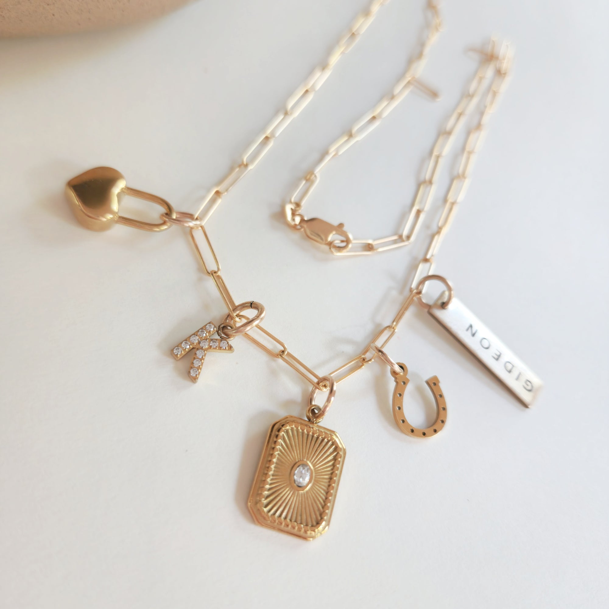 Gold necklace with various charms on a light background