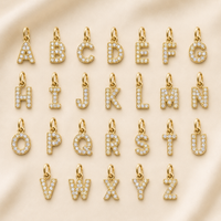 Gold-tone CZ initial charm encrusted with cubic zirconia stones on a white background