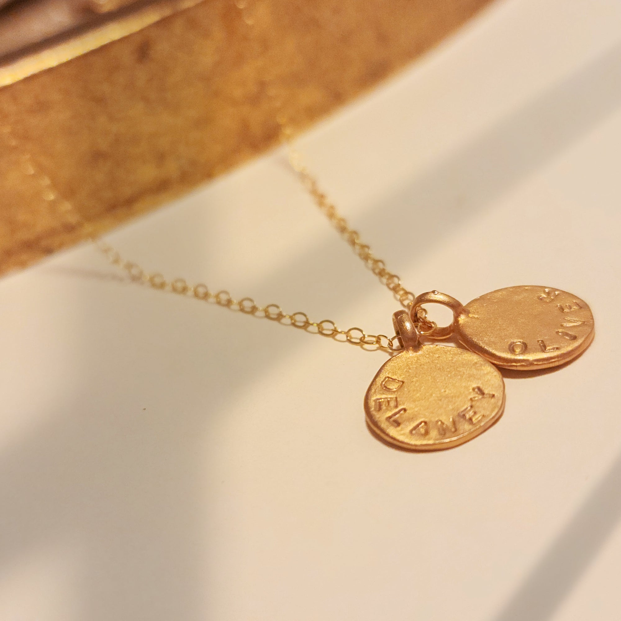 Gold necklace with two round pendants on a light background