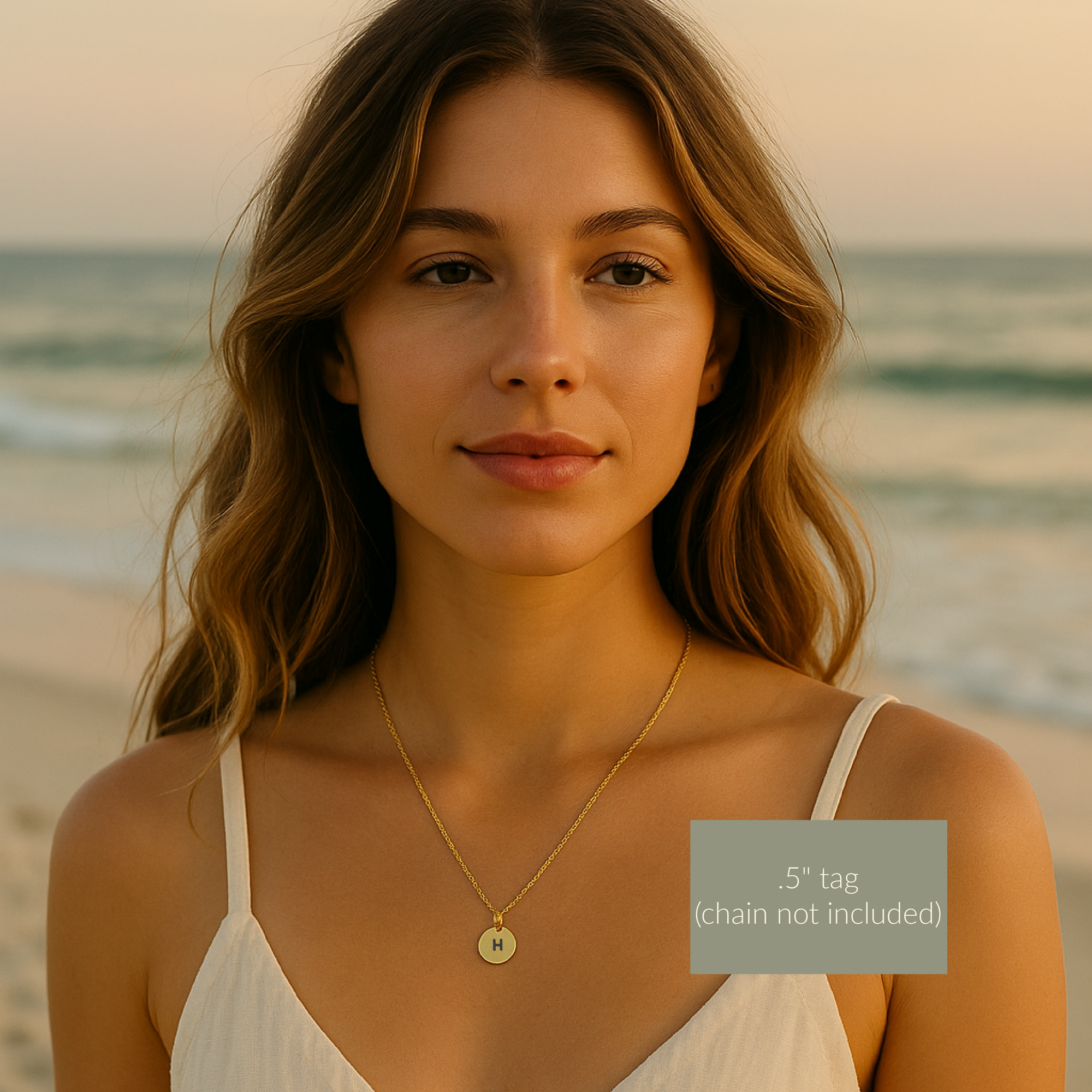 Woman wearing a gold necklace with a 'H' pendant on a beach