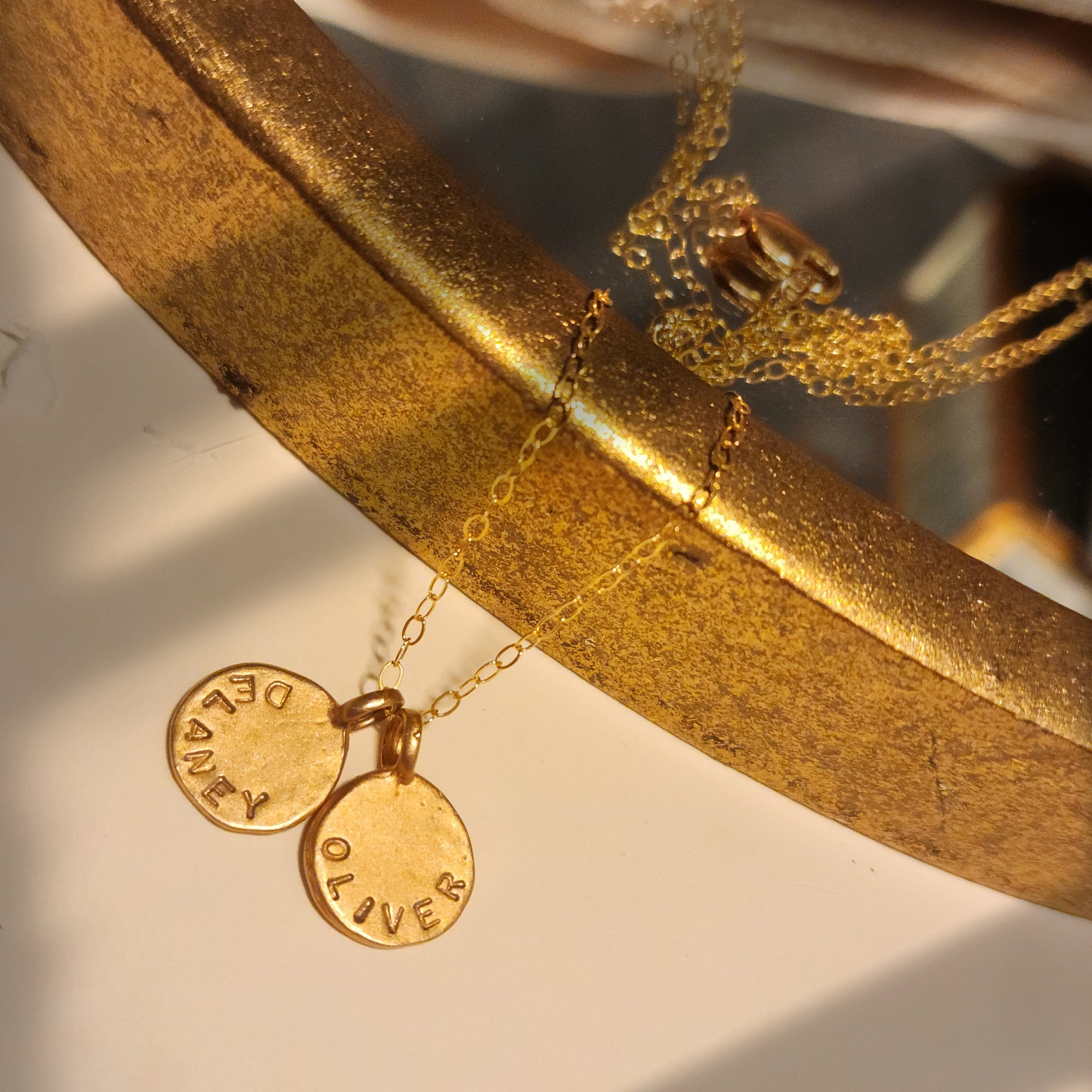 Gold bracelet with engraved charms on a reflective surface