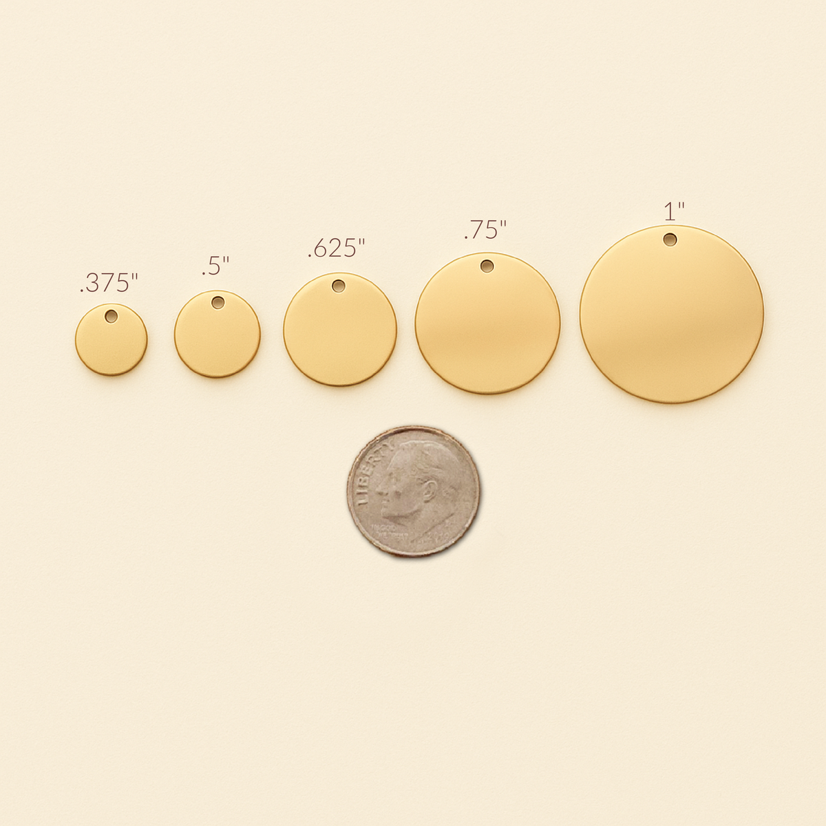 Gold circular pendants of different sizes with a coin for scale on a beige background