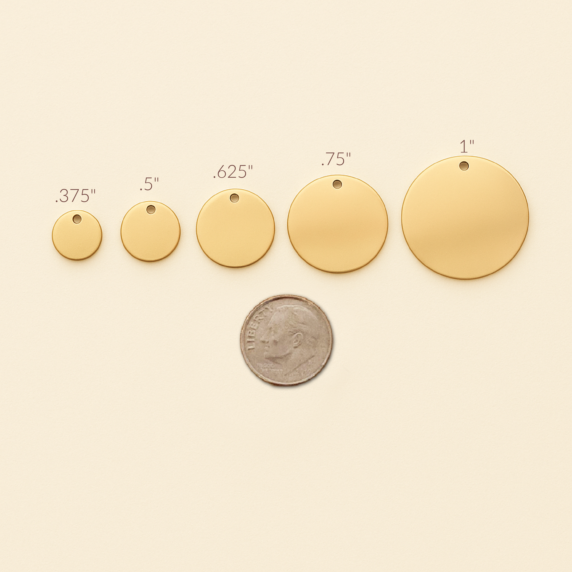 Gold circular pendants of different sizes with a coin for scale on a beige background
