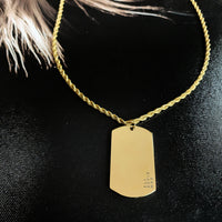 Gold necklace with a dog tag on a black background