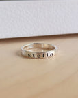 A silver stacking ring with the name 'stella' engraved on it, displayed against a white background.