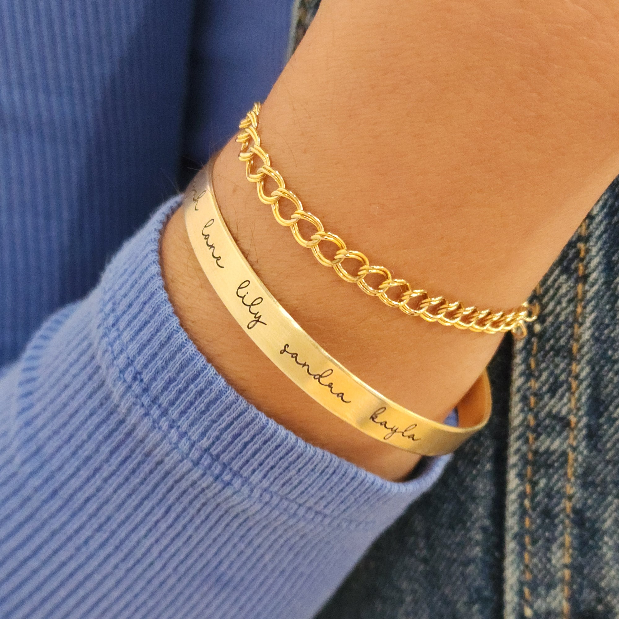 A gold-colored cuff bracelet with custom names engraved 