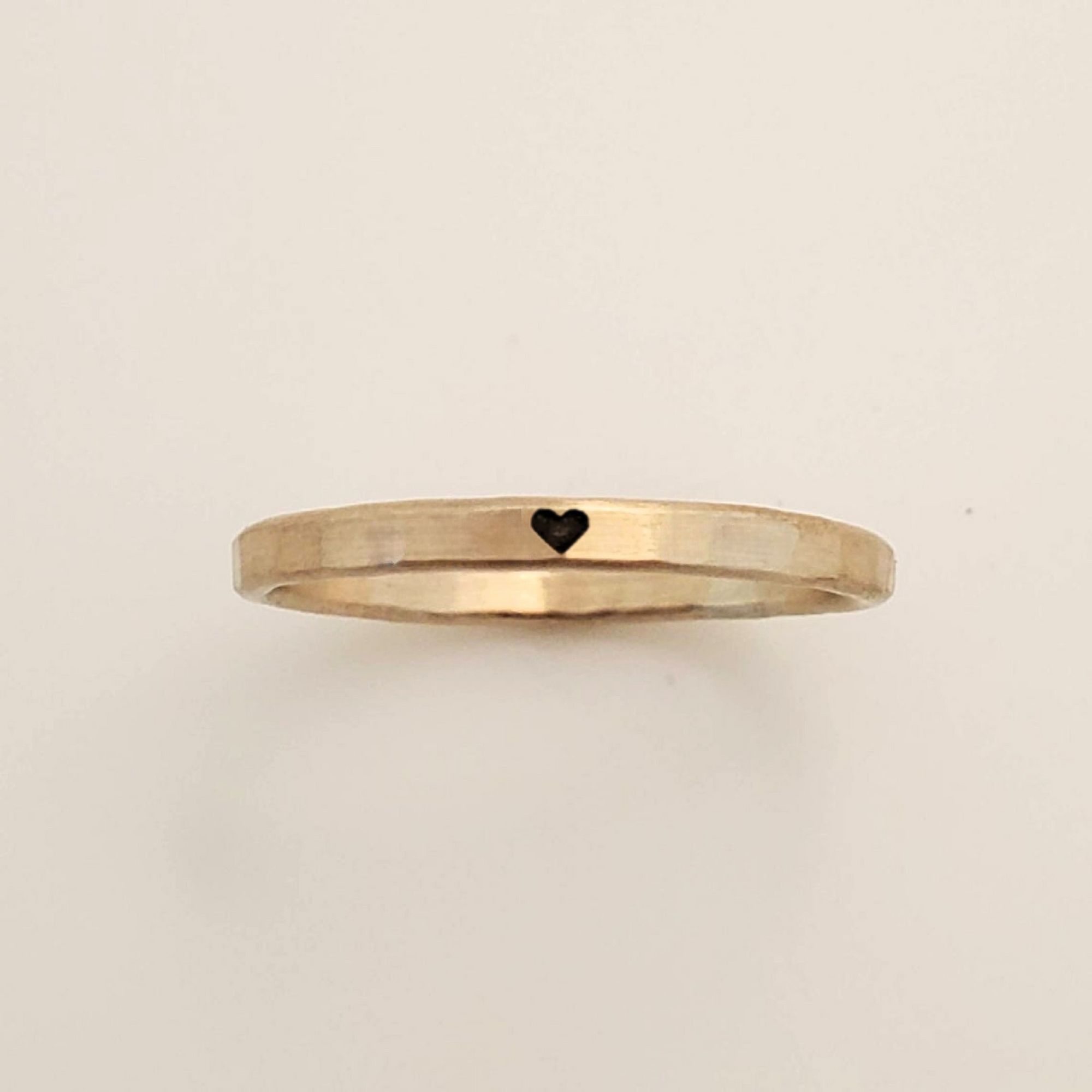 Gold ring with a heart symbol on a beige background