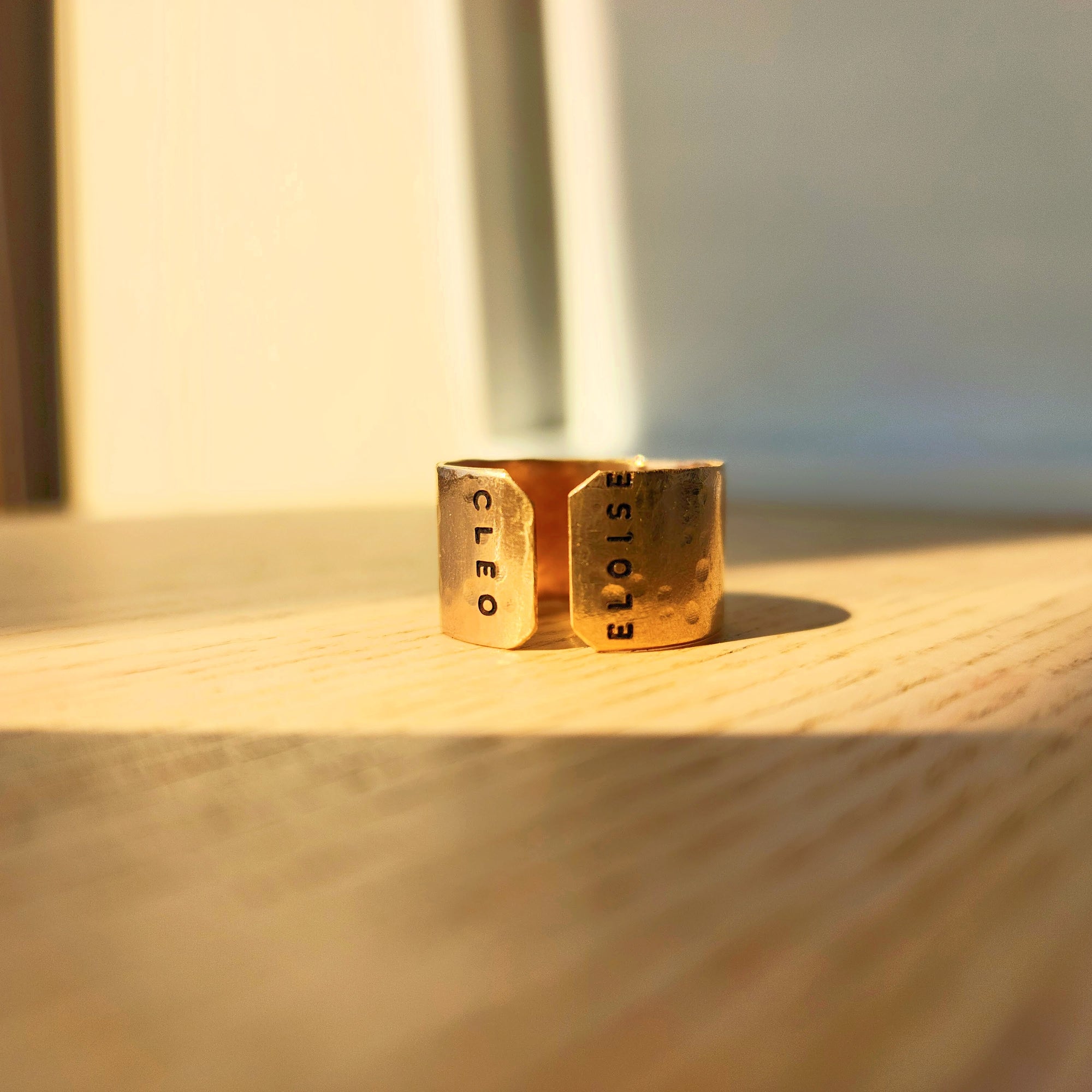 Handcrafted personalized gold name cuff ring photographed in warm studio light