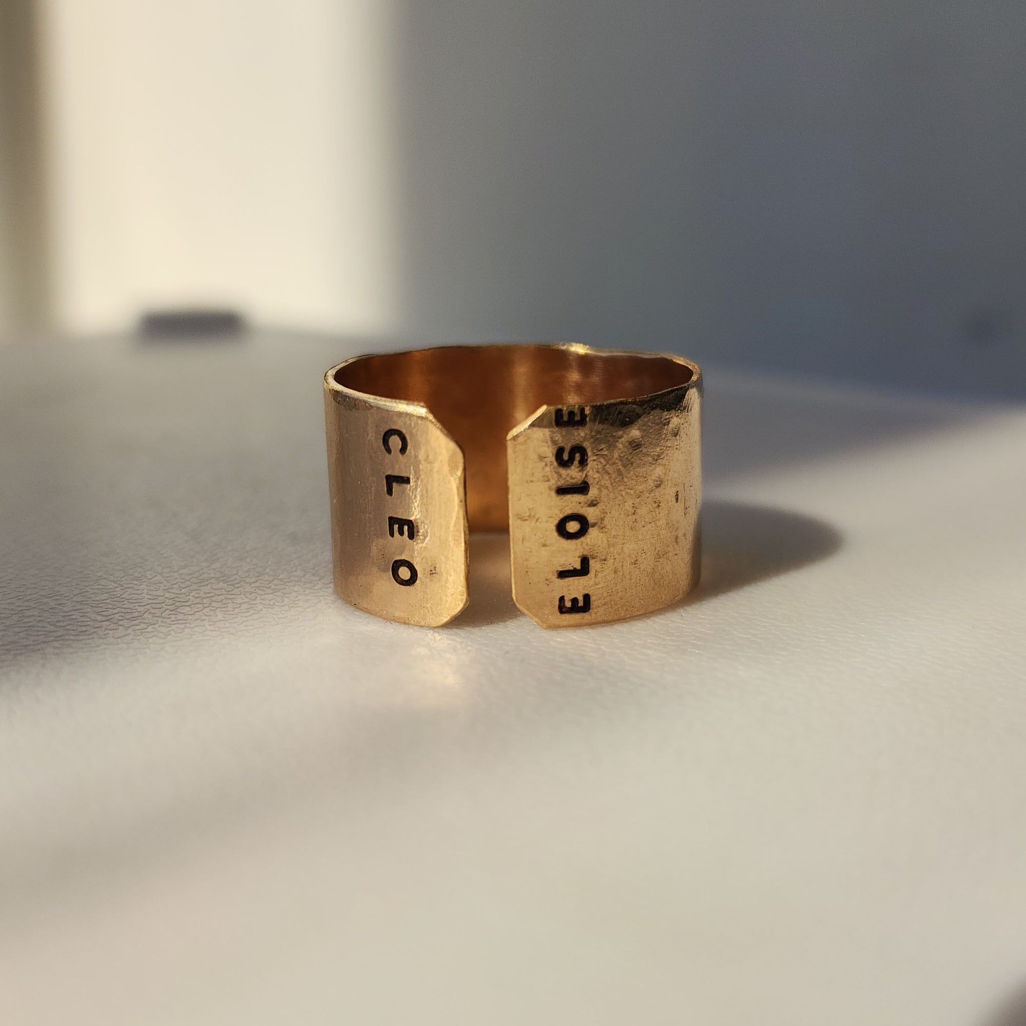 Handcrafted personalized gold name cuff ring photographed in warm studio light