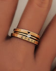 A hand wearing three yellow gold rings stacked on one another, with the top ring featuring a heart, second stone is a clear stone and the word 'grace' engraved on  the bottom.

Details