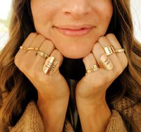 Stack of handmade personalized gold name rings for moms and families