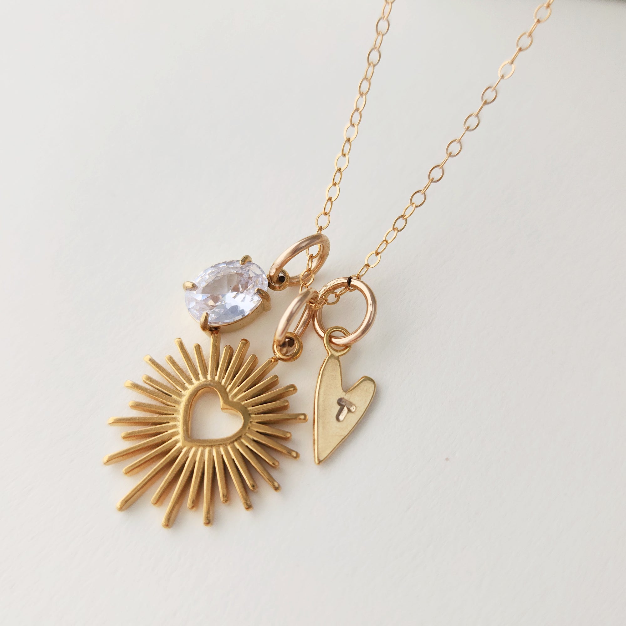 Gold necklace with heart-shaped pendants on a light gray background