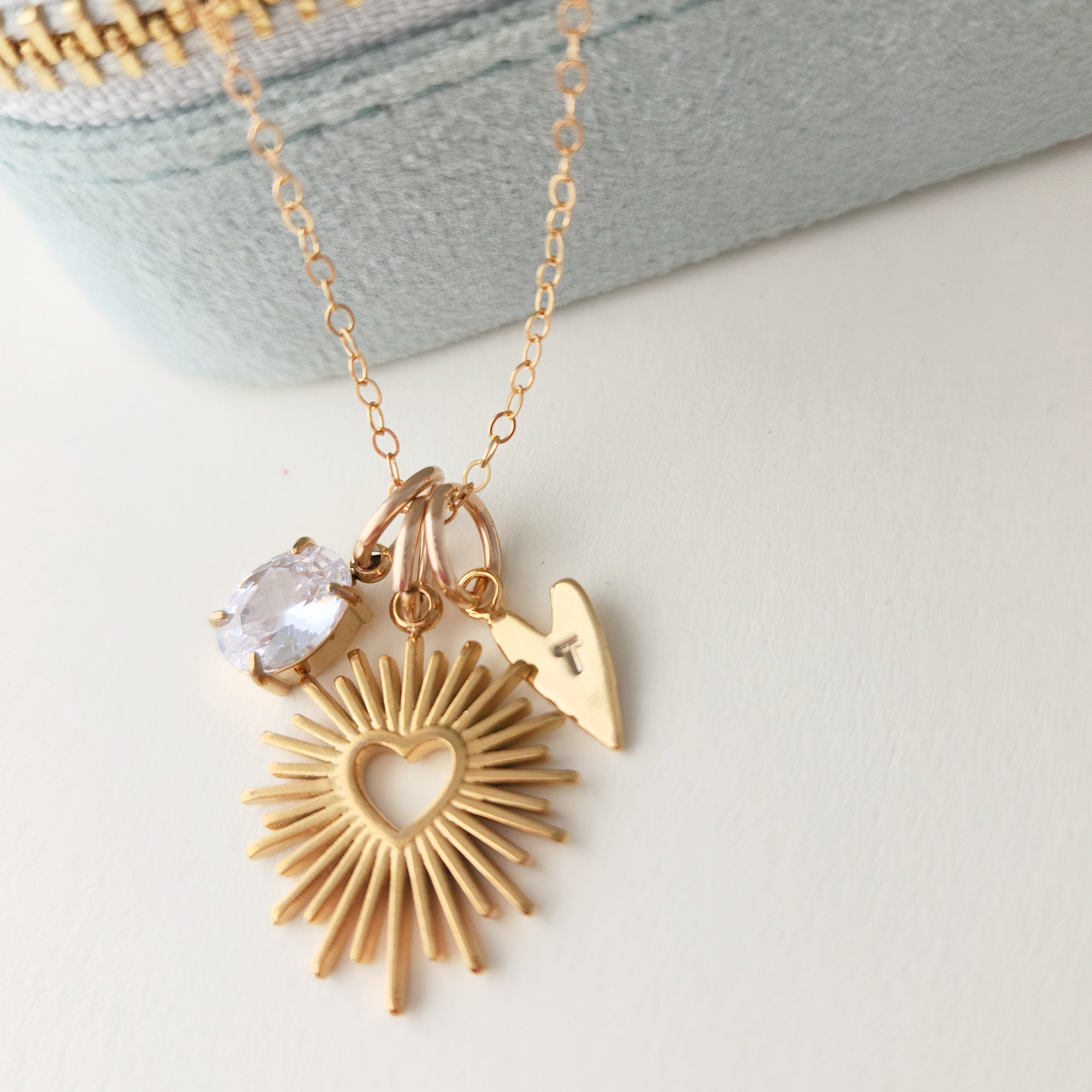Gold necklace with heart-shaped pendant and clear stone on a light background