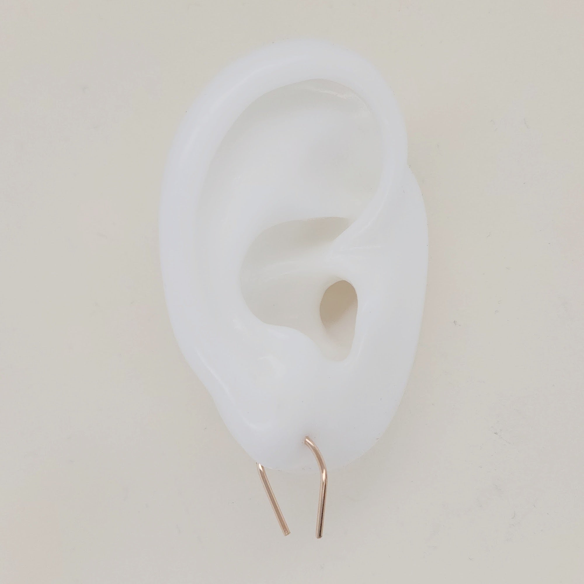 Gold U-shaped earrings shown on white silicone ear display